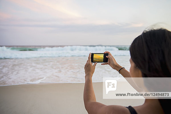 Frau  die ein Bild von den Wellen macht  die sich dem Ufer am Strand von Copacabana nähern