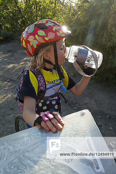 A Girl Drinking Water From A Bottle Next To A Trail Sign While Mountain Biking On The Horse Gulch Trail System