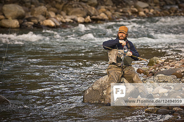 Ein Fliegenfischer macht eine Pause auf einem Felsen in Squamish  British Columbia.