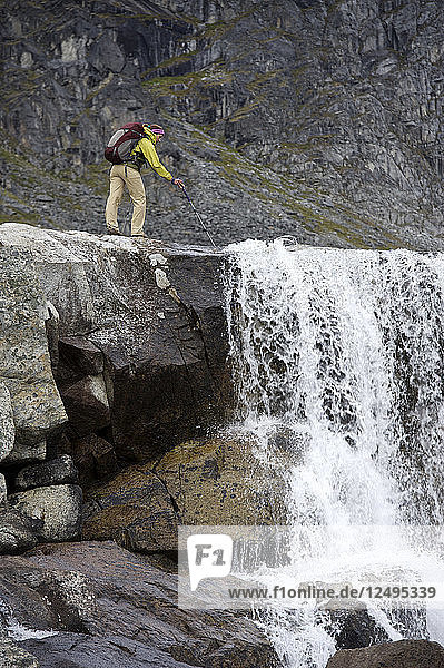 Eine Wanderin überblickt einen Wasserfall während einer Rucksacktour zu den Reed Lakes in den Talkeetna Mountains in der Nähe von Palmer  Alaska  August 2011.