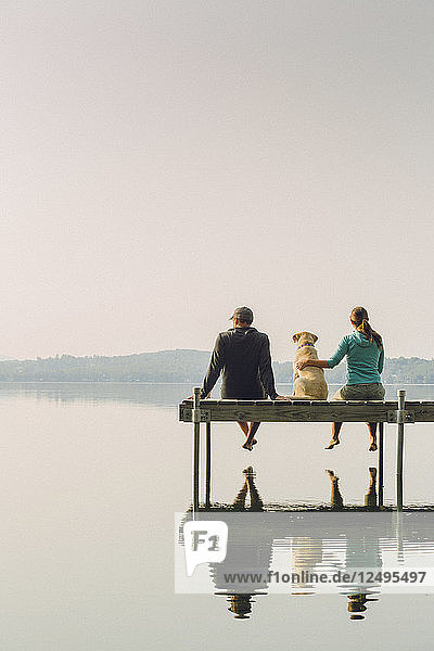 Mann und Frau mit ihrem Hund sitzen auf Dock auf Kaspischen See