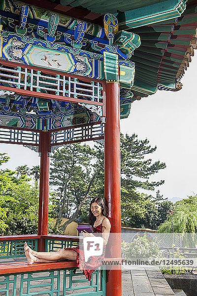 Woman using tablet at an oriental garden