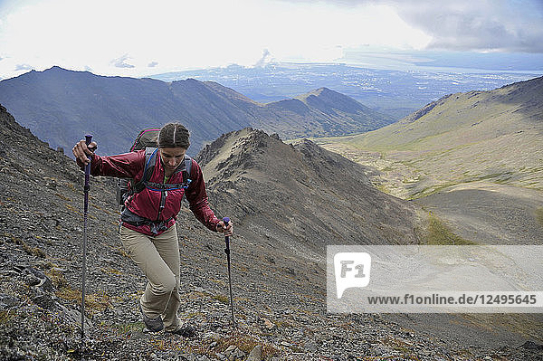 Female hiker starts her ascent up Tikishla Peak (5230-feet) with Anchorage and Knoya Peak in the distance of the Snowhawk Valley of the Chugach Mountains north of Anchorage  Alaska August 2011. Even though the Snowhawk Valley is home to 5 of 12 peaks over 5000-feet in the Chugach Front Range it see very little traffic due to difficult access. In the Dena'iai language  Tikishla means black bear.
