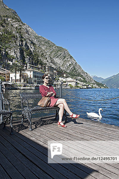 Frau  die am Hafen von Limone am Gardasee in Norditalien sitzt