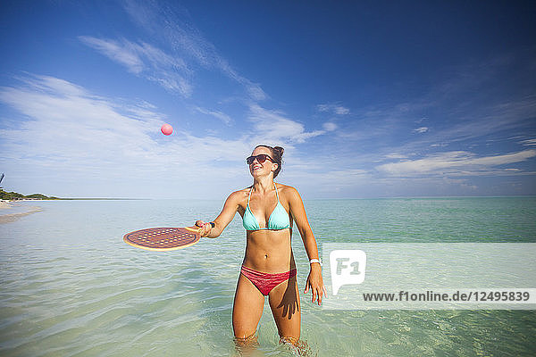 Eine junge Frau spielt während ihres Urlaubs in Cayo Coco  Kuba  mit einer Strandversion von Racquetball.