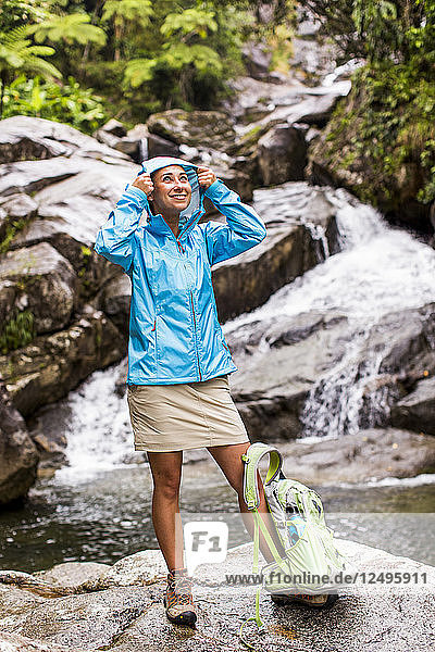 Porträt einer Frau  die eine Jacke vor einem Wasserfall und einem Bach trägt