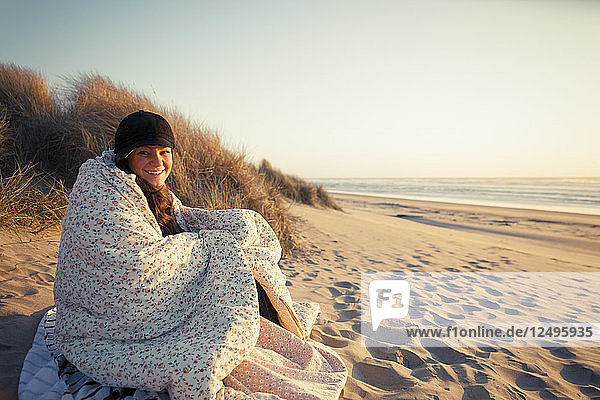Eine Frau  eingewickelt in eine Decke am Strand.