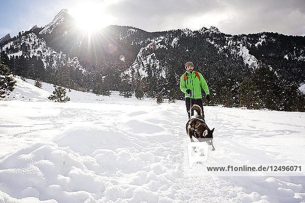 A guy and his dog on a sunny winter day walk through Chautauqua Park in Boulder  Colorado.