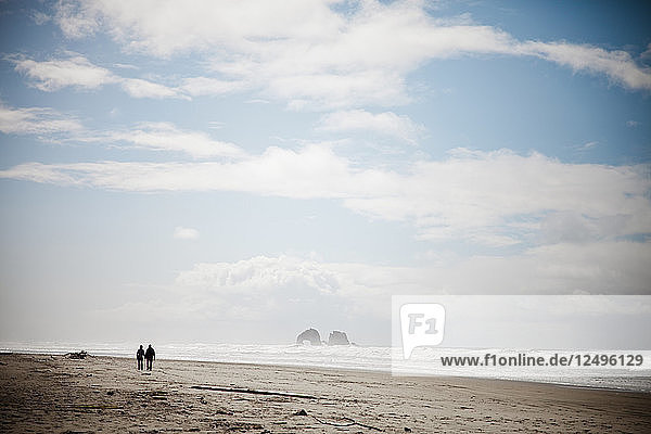 A couple walks near Twin Rocks on Rockaway Beach  Oregon.