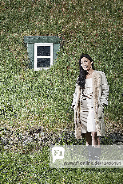 Koreanische Frau posiert vor einem mit Gras bedeckten Dach