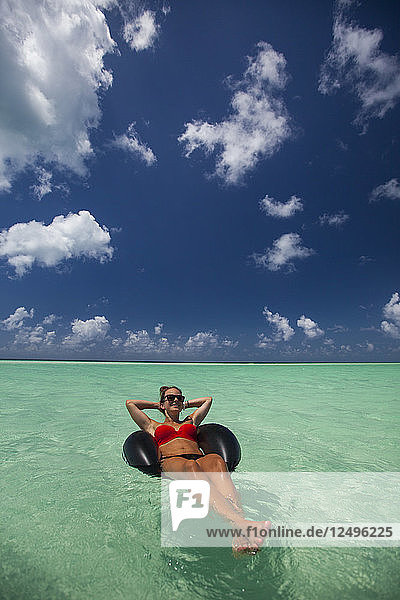 A young woman wearing a bikini relaxes on an inflatable tube in turquoise water while on vacation in Cayo Coco  Cuba.