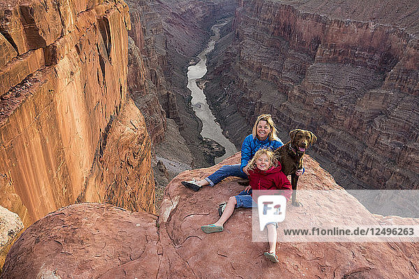 Eine Mutter  eine Tochter und ihr Hund sitzen am Rande des Toroweap Overlook über dem Colorado River  Grand Canyon National Park  Fredonia  Arizona.