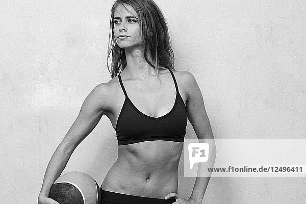 Fitnessmodel Maria Ambrose posiert mit einem beschwerten Ball vor einem Zementhintergrund in Brooklyn  New York.