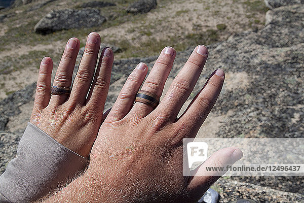A young couple wear matching wooden rings during a backpacking trip.