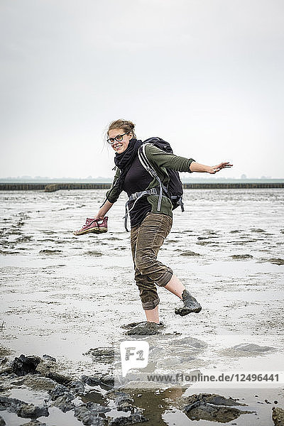 Junge Frau beim Spaziergang im Wattenmeer bei Ebbe  Husum  Nordfriesland  Schleswig-Holstein  Deutschland