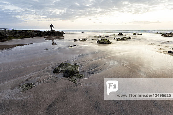 Ein Fotograf stellt sein Stativ auf  um Langzeitbelichtungsfotos vom Meer zur goldenen Stunde auf Fuerteventura zu machen.