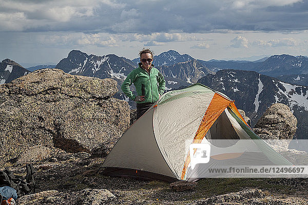 Eine Rucksacktouristin steht neben ihrem Zelt beim Zelten im Cathedral Lakes Provincial Park  British Columbia  Kanada.