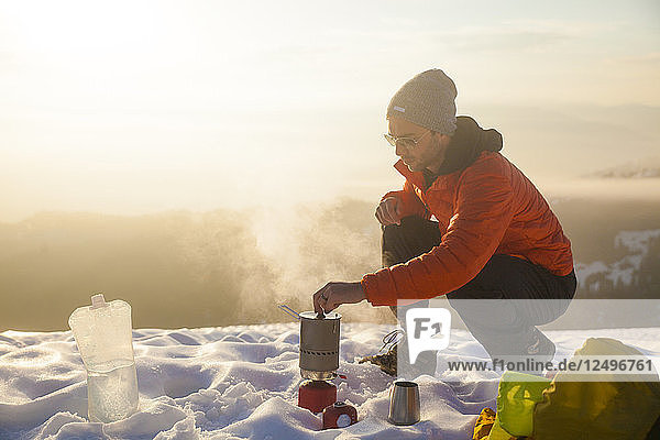 Ein Bergsteiger kümmert sich um sein kochendes Wasser auf einem Campingkocher beim Zelten in den Bergen von British Columbia  Kanada.