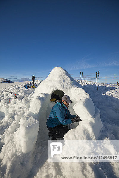 Ein Mann baut einen Eingangstorbogen zu seinem Iglu am Seymour Mountain  Kanada