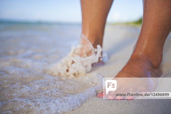 Surf washes over a young womans feet at a beach in Cayo Coco  Cuba.
