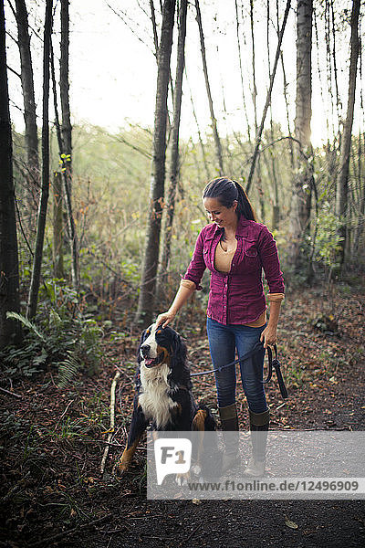 Porträt einer jungen Frau  die sich mit ihrem Berner Sennenhund in der freien Natur vergnügt.