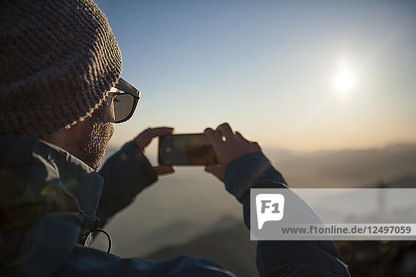 Ein Mann fotografiert mit seinem Handy die Aussicht vom Gipfel des Sauk Mountain in den North Cascades  Washington.