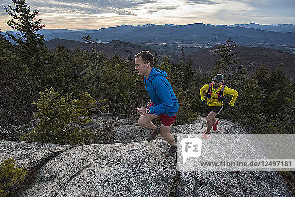 Trail runners on steep and clean granite slabs overlooking Mount Washington and the White Mountains.