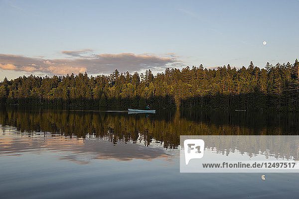 Person Fliegenfischen auf einem Kanu in einem stillen Teich in Maine