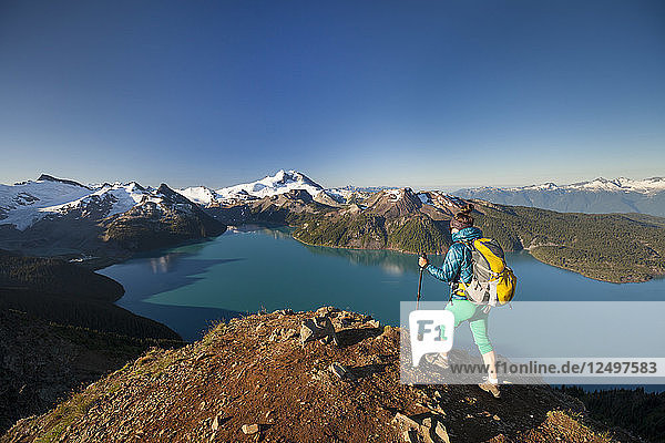 A backpacker reaches the summit of Panorama Ridge  overlooking Garibaldi Lake in Garibaldi Provincial Park  British Columbia  Canada.