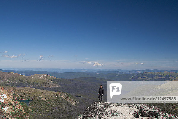 A hiker stands on the summit of Grinface Mountain in Cathedral Lakes Provincial Park  British Columbia  Canada.