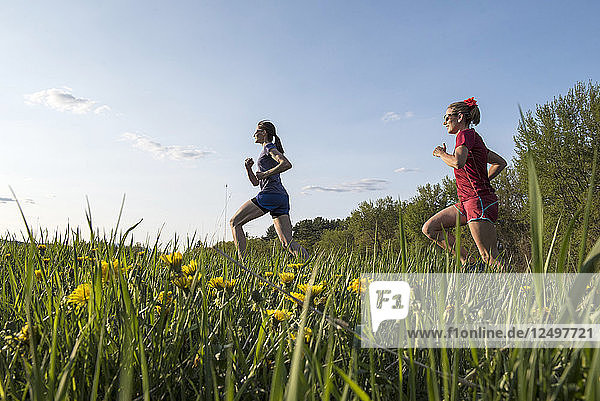 Two Female Runners Running On Grassy Field