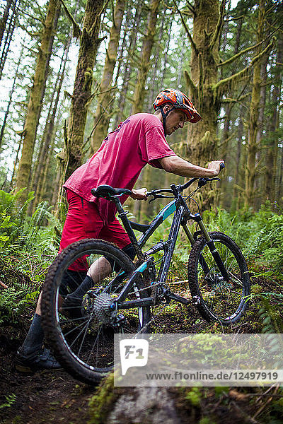 A mountain biker pushes his bike up a trail in North Vancouver  British Columbia  Canada.