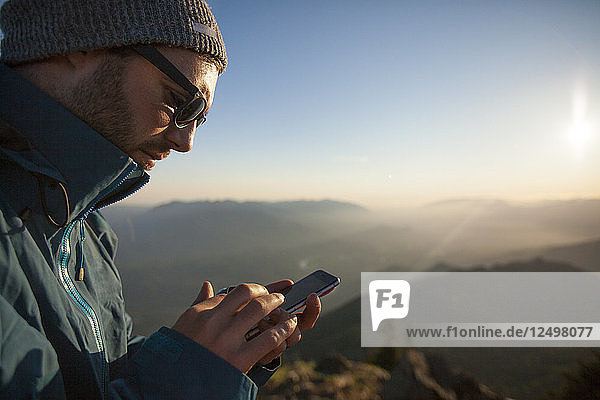 Ein Mann benutzt sein Smartphone  während er sich in der Natur aufhält.