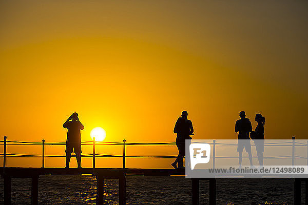 Silhouette von Touristen Menschen Erkundung Beach Resort während Sonnenuntergang
