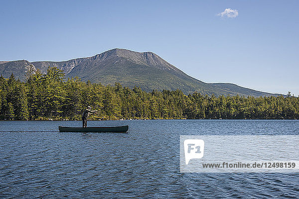 Fisherman casting in Kidney Pond with Mount Katahdin in the background.