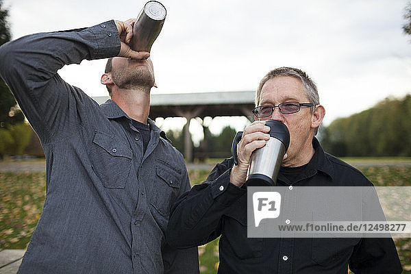 A Father And His Son-in-law Drinking Out Of Coffee Mugs