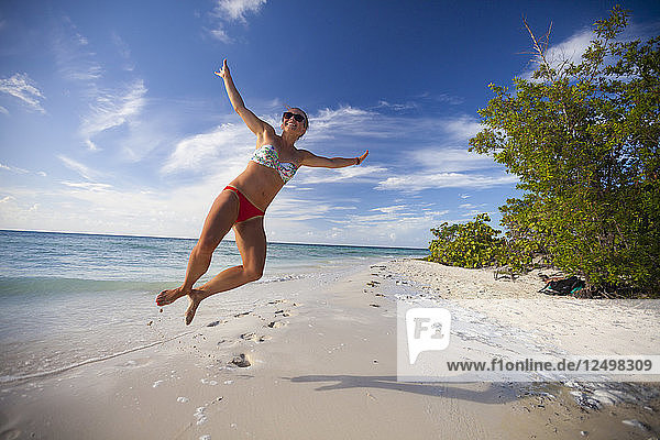 Ein junger attraktiver Mann springt in die Luft und macht am Strand von Cayo Coco  Kuba  einen Fersenklick.