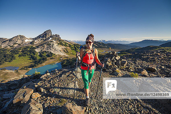 A young woman hiking on the Panorama Ridge Trail with Black Tusk Mountain in the background in Garibaldi Provincial Park  British Columbia  Canada.