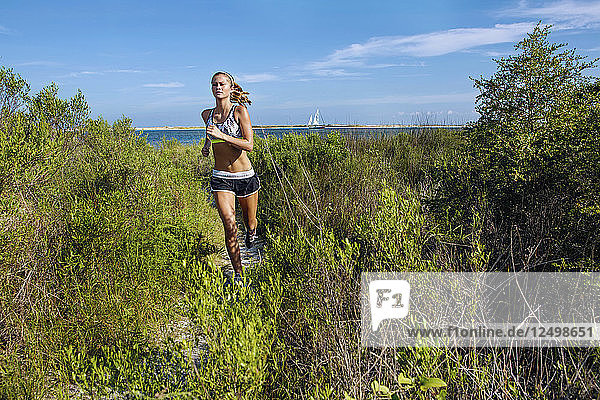 Eine junge Frau trainiert und läuft auf der Uferpromenade im Big Lagoon State Park.