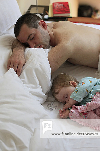 Daughter and father sleeping in bed.