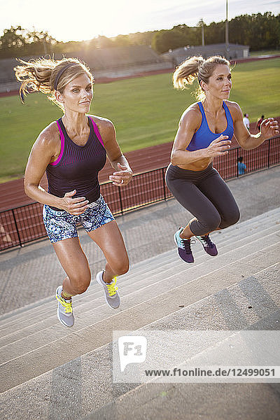 Zwei Frauen springen auf einer Treppe im Stadion