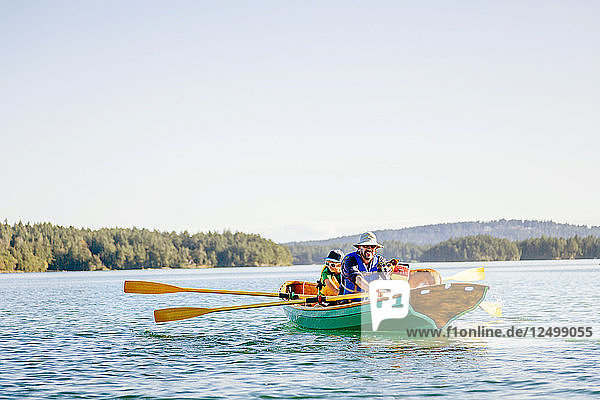 Ein Mann mit seinem Sohn und ihrem Hund in einem Ruderboot in Deer Harbor  Orcas Island  Washington  USA