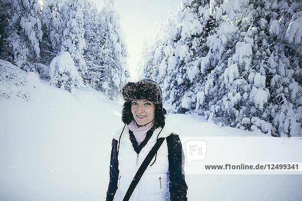 Porträt einer im Wald stehenden Frau im Schnee