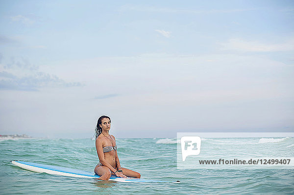 Eine junge Frau paddelt auf einem Brett in den Gewässern des Golfs von Mexiko.