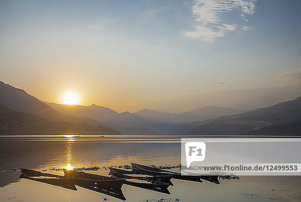 Der Sonnenuntergang über versunkenen Fischerbooten auf dem Phewa-See in Pokhara  Nepal