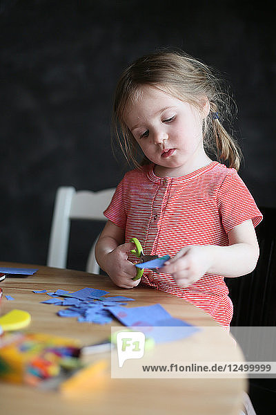 Ein Vierjähriger schneidet Papier und bastelt zu Hause.