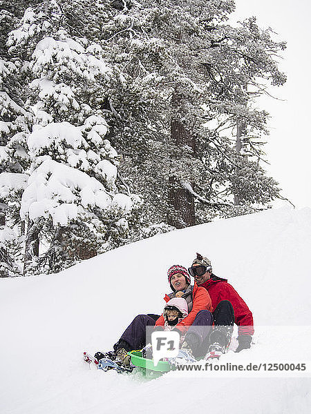Parents and kids sledding in fresh snow in front of the Peter Grubb ski hut  Sierra Nevada
