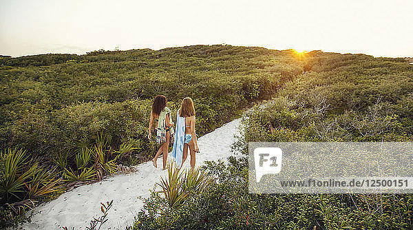 Zwei junge Frauen wandern auf Pfaden durch eine Sanddüne an einem Strand in Florida.