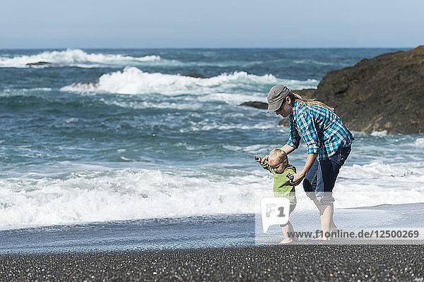 Mutter spielt mit ihrer kleinen Tochter am Strand an der kalifornischen Küste
