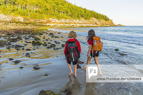 Teenage Boy And Girl Walking On Beach Barefoot In Acadia National Park